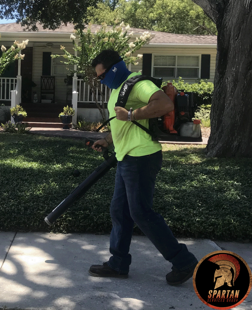 Man blowing off sidewalk wearing safety gear.